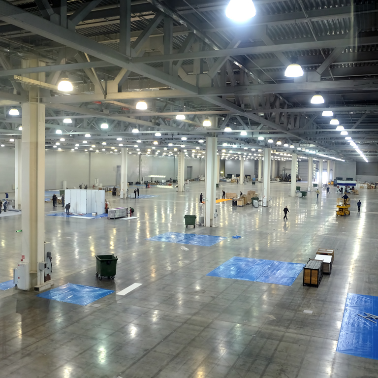 Large empty warehouse interior in an industrial building with high vertical columns with and high ceiling and artificial lighting horizontal view