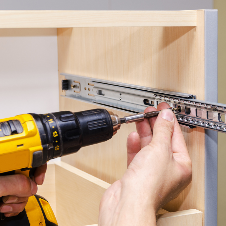 Assembling furniture from chipboard, using a cordless screwdriver, close up